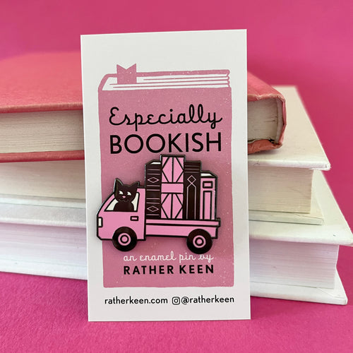 The Book Truck enamel pin seen on its display card