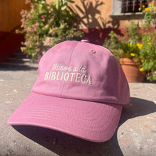 dusty pink embroidered vamos a la biblioteca hat posed outside a library