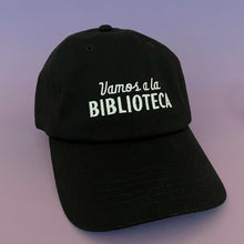 black dad hat with the words Vamos a la Biblioteca embroidered in white