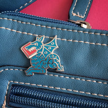 blue Book Wyrm enamel pin on leather bag