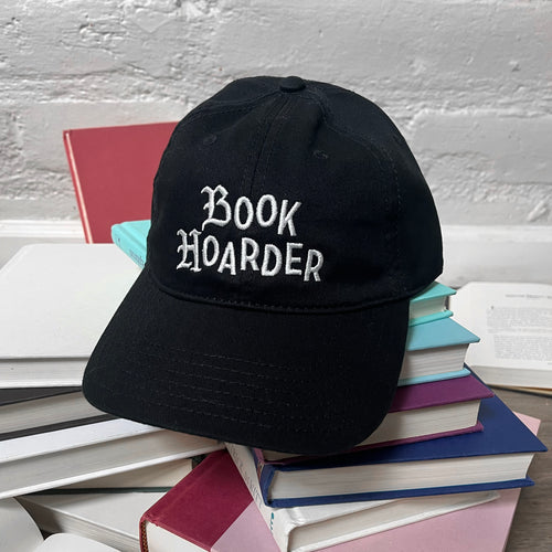 Book Hoarder embroidered hat on pile of books