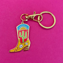 The Cactus Boot keychain by Rather Keen is a gold metal and enamel color charm of a boot featuring an illustration of a cactus on its side 