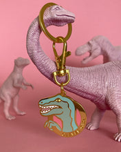 Clever Girl velociraptor keychain dangling from a pink toy dinosaur