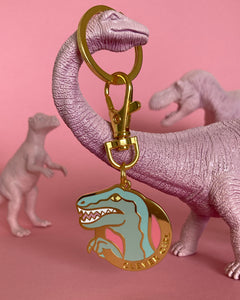 Clever Girl velociraptor keychain dangling from a pink toy dinosaur