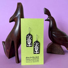 Saguaro cactus earrings by Rather Keen - black metal door-shape with white illustration of a cactus