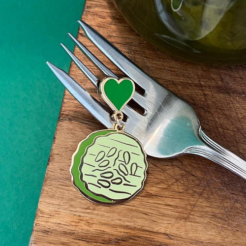 Pickle earring - a pickle slice dangling from a green heart stud displayed on fork