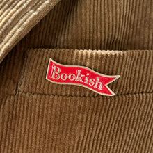 Red and enamel pin shaped like a bookmark with the word "Bookish" on it in gold letters.