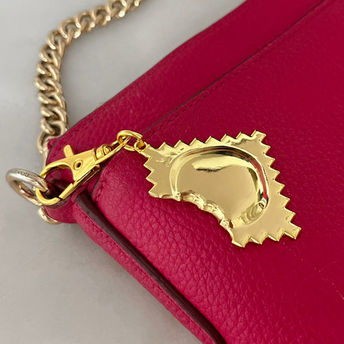 golden ravioli bag charm on red purse