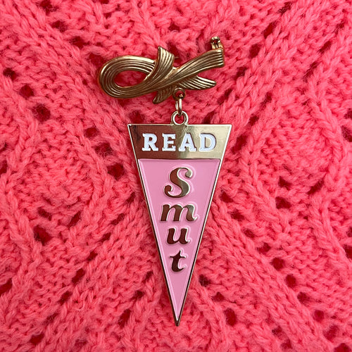 Triangle Read Smut charm linked to gold bow pin