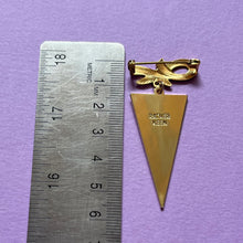 Ruler placed next to pin and charm to show height