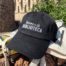 Black hat embroidered with Vamos a la Biblioteca photographed at library