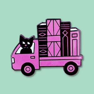 The Book Truck enamel pin by Rather Keen. This black and pink enamel pin is shaped like a Japanese kei truck loaded with giant books and driven by a cute cat.