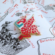 Red Book Wyrm enamel pin by Rather Keen. This pin is a medieval manuscript style dragon eating a book.